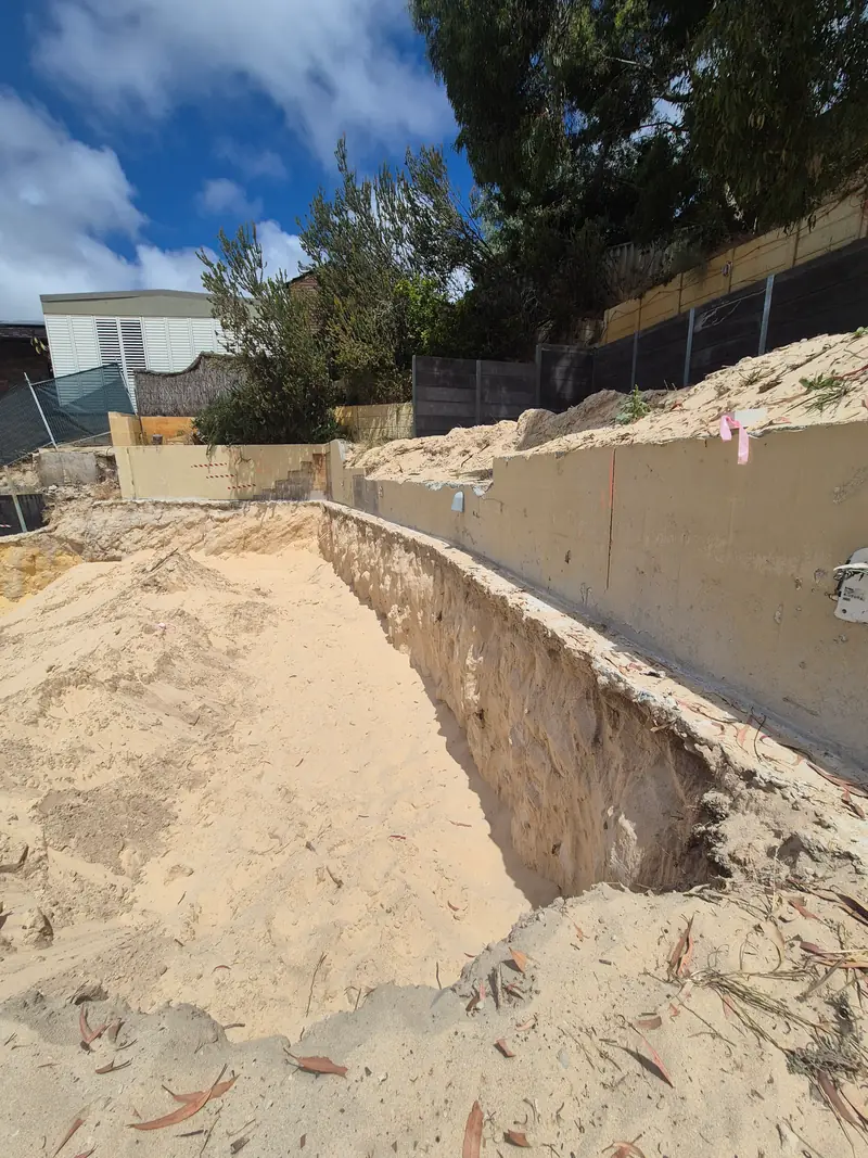 Sandy trench excavated along the base of a retaining wall